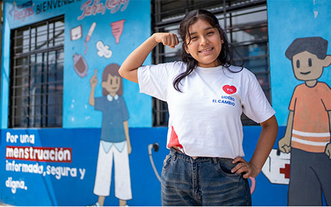 Girl smiling and looking confident with her arm flexed showing strength