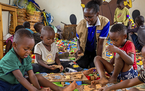 Adult seated with young children working on wooden puzzles